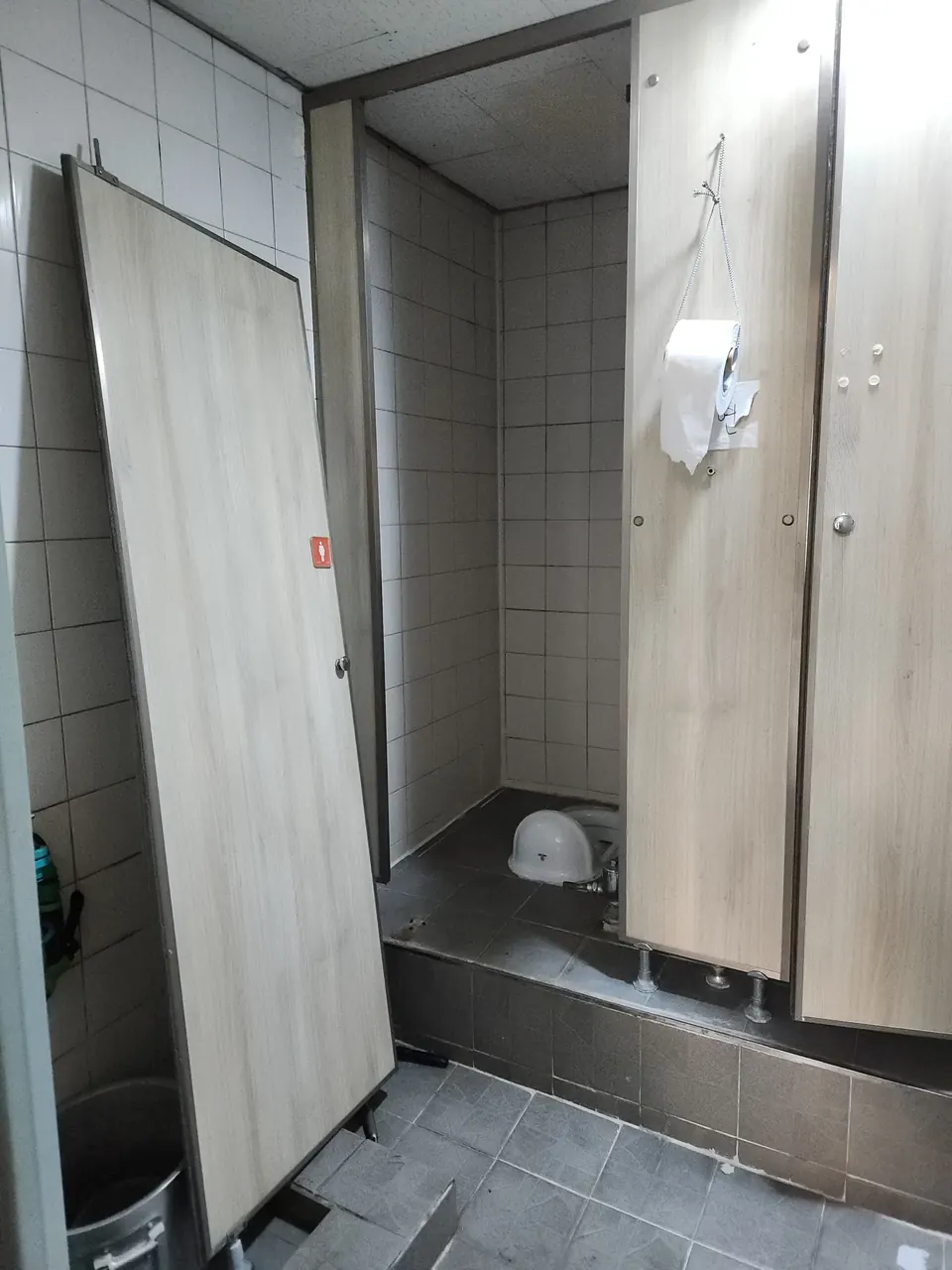 화장실큐비클문짝교체 떨어진 문짝이 벽에 기대어 있는 상가 화장실